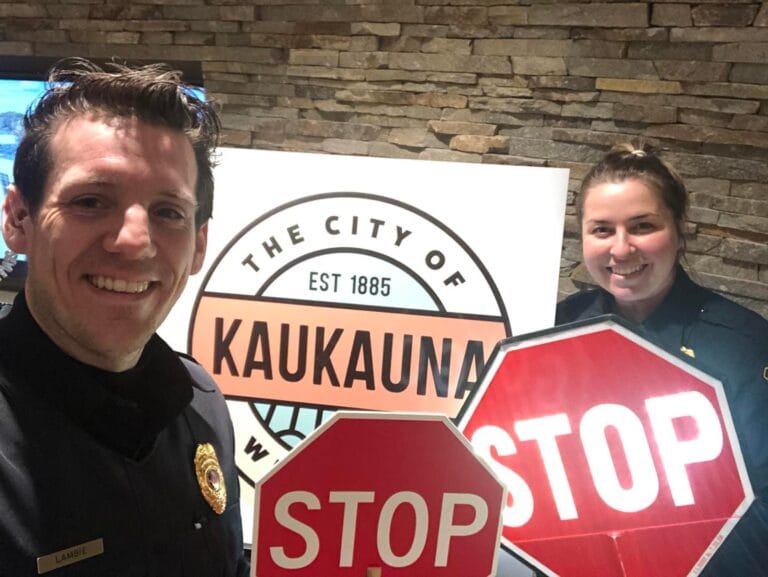 Police staff stand with stop signs as they fill crossing guard duties