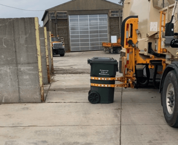 Garbage collection truck grabbing a trash bin.