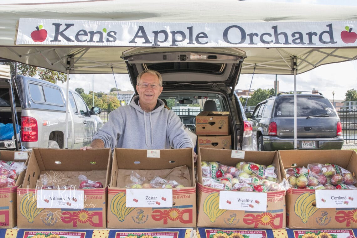 Man stands near apples from Ken's Apple Orchard