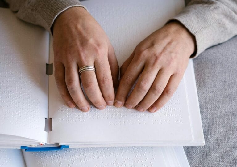 Stock image of hands over braille text by Mikhail Nilov.