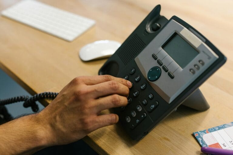 Stock picture of someone's hand dialing a number on an office phone. Picture by Rdne Stock Product.
