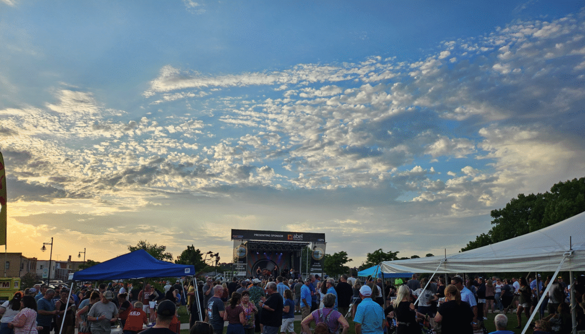Picture of a stage with crowd including a blue sky with clouds