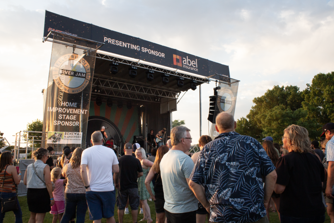 Image taken from the crowd looking up at a stage with a band performing.