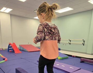 Little girl walks on a balance beam in the new tumbling room
