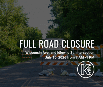 A road closure notice for Wisconsin Ave. and Idlewild intersection scheduled for July 10, 2026, from 7 AM to 1 PM. The background shows barricades on a tree-lined road. A logo with K and WI is present at the bottom right.