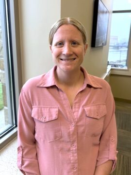 Woman stands next to a window smiling