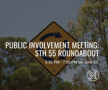 A roundabout road sign is in front of trees. Text overlaid on the image reads: 