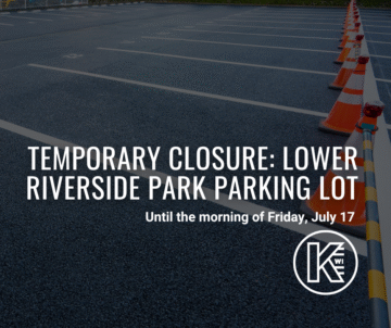 The image shows an empty parking lot with traffic cones arranged in a line. Overlaid text reads, 